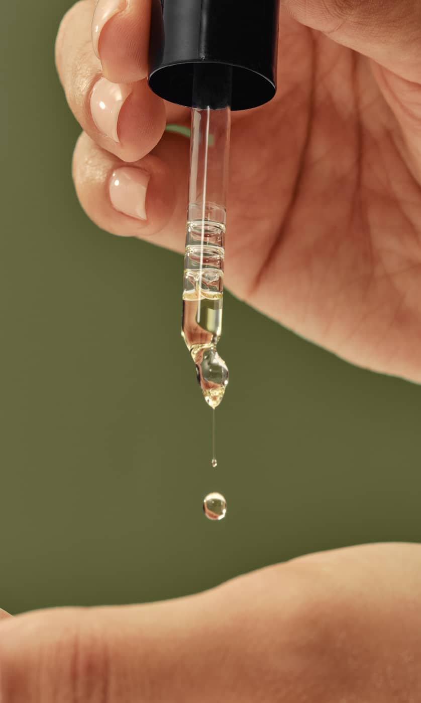 Dropper-releasing-Prose-Custom-Hair-Oil-into-a-hand-with-a-green-backdrop.jpg
