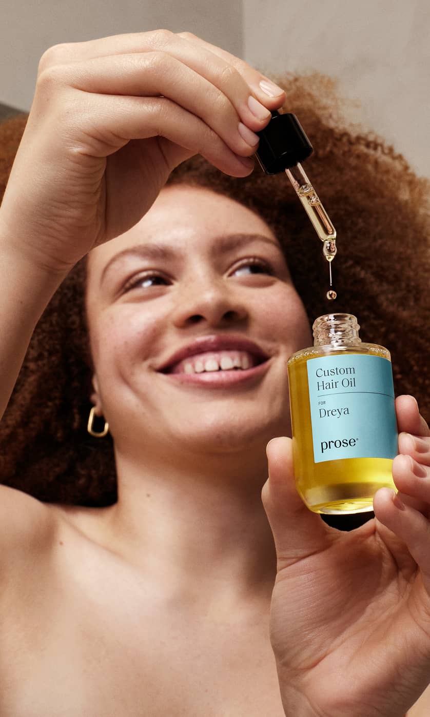 Smiling-woman-using-Prose-Custom-Hair-Oil-with-overlay-text-saying-80_-saw-less-frizz-using-personalized-Prose-hair-oil.jpg